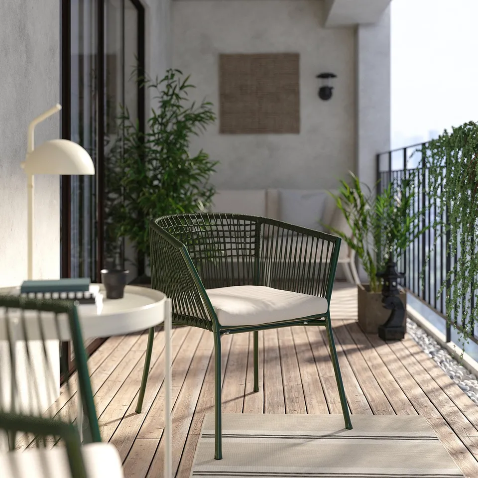 Modern balcony with green SEGERÖN chair, white cushion, wooden floor, plants, and grey walls.
