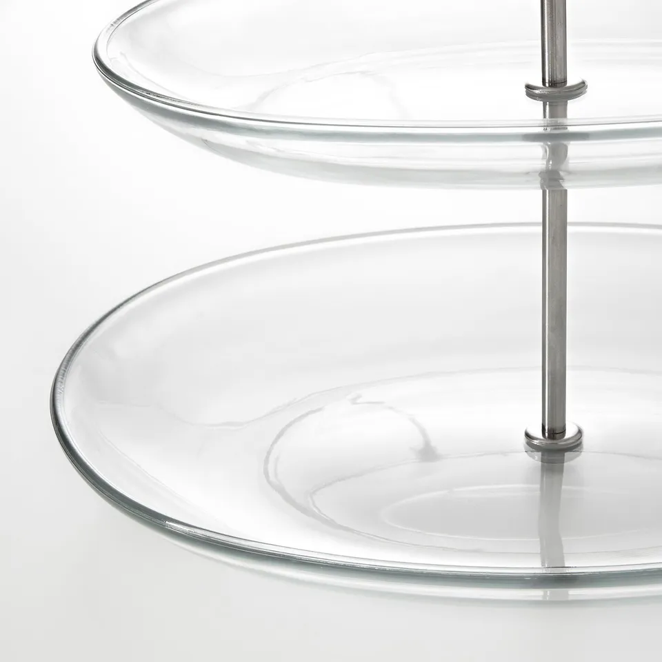 Clear three-tiered glass serving stand with stainless steel poles; sleek, modern design.