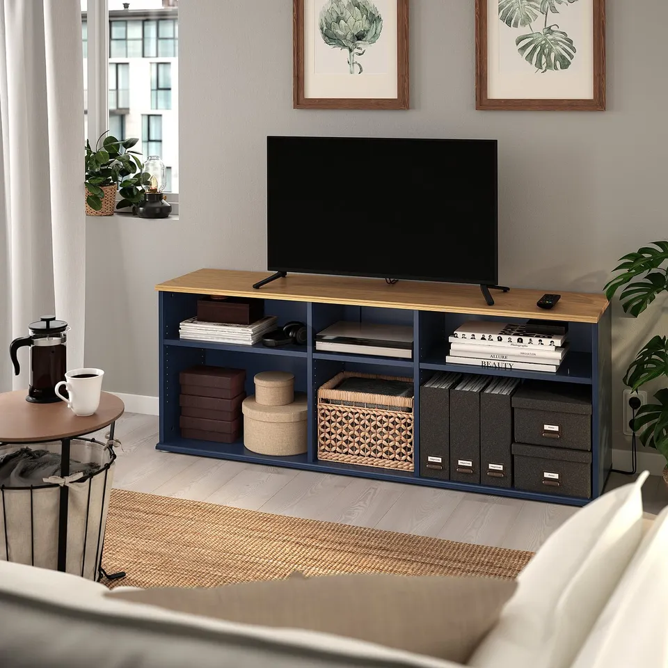 Modern living room setup with SKRUVBY tv stand in blue-gray & oak, flat-screen tv, books, plants, and a cosy rug.
