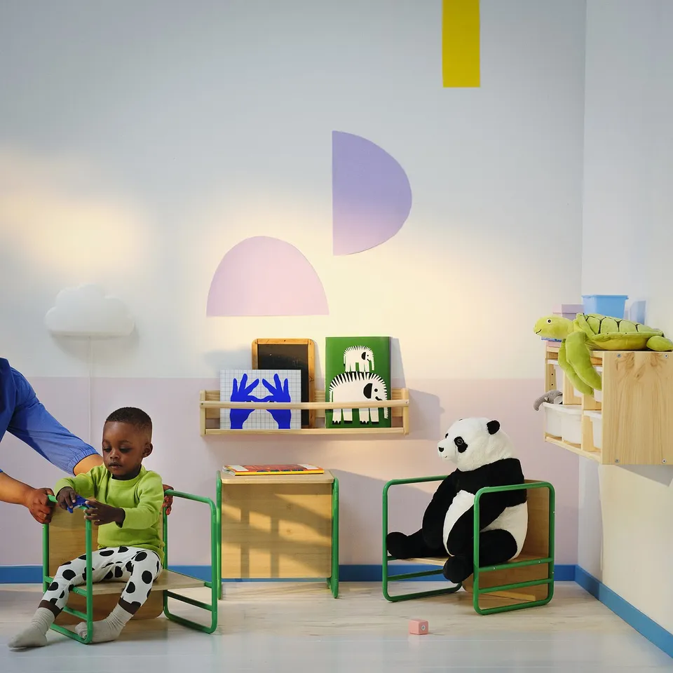 Child in green chair with panda toy & books.