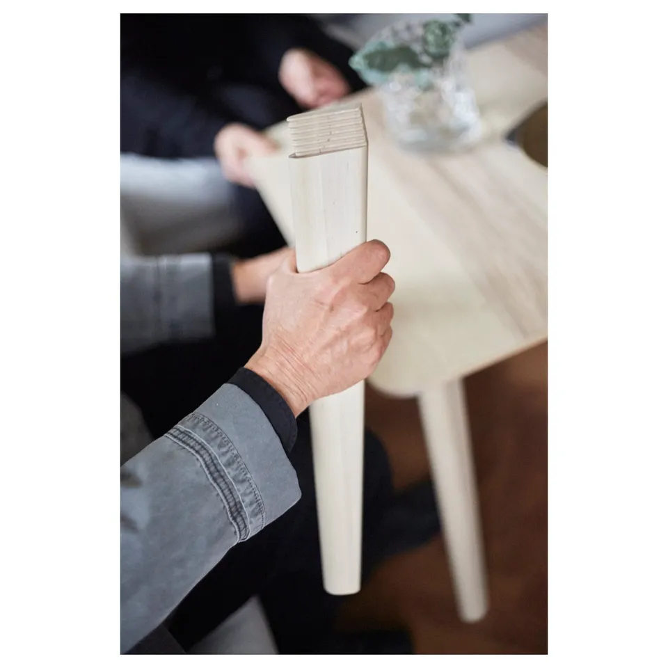 Person holding a white table leg, showcasing its smooth finish and sturdy build.
