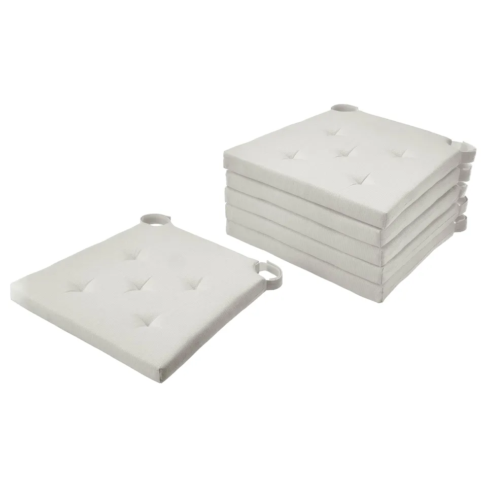 Stack of four white JUSTINA cotton chair cushions with tufted design.