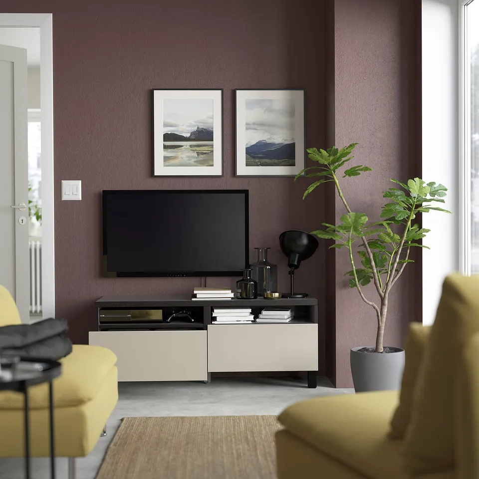 Modern living room with purple walls, yellow couch, black tv on storage unit with open drawers and framed photos.
