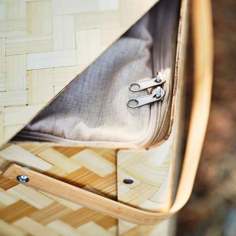 Zipped mesh compartment in wicker basket, showcasing quality craftsmanship.