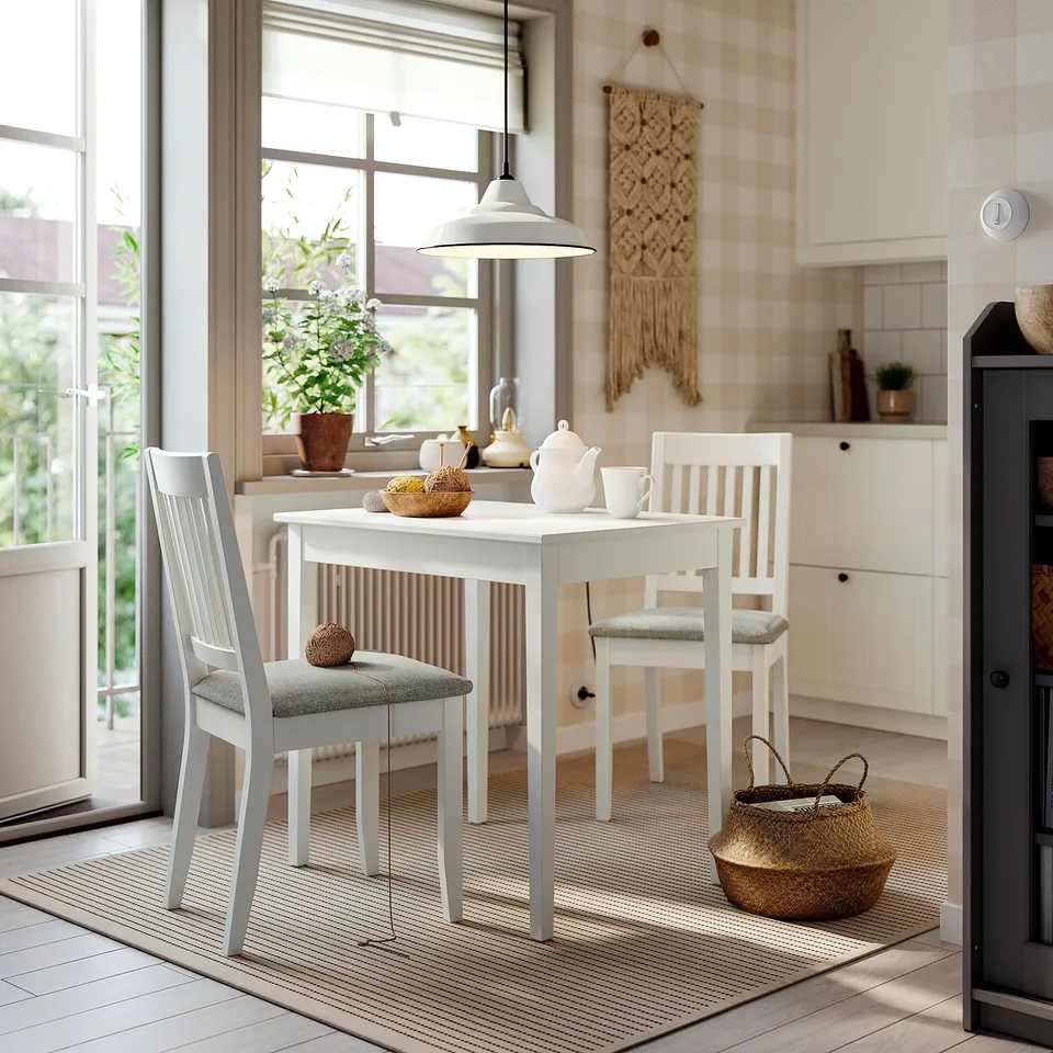 Modern dining setup with NÄSINGE table, chairs, cushioned seats, basket, striped rug, and kitchen macrame.