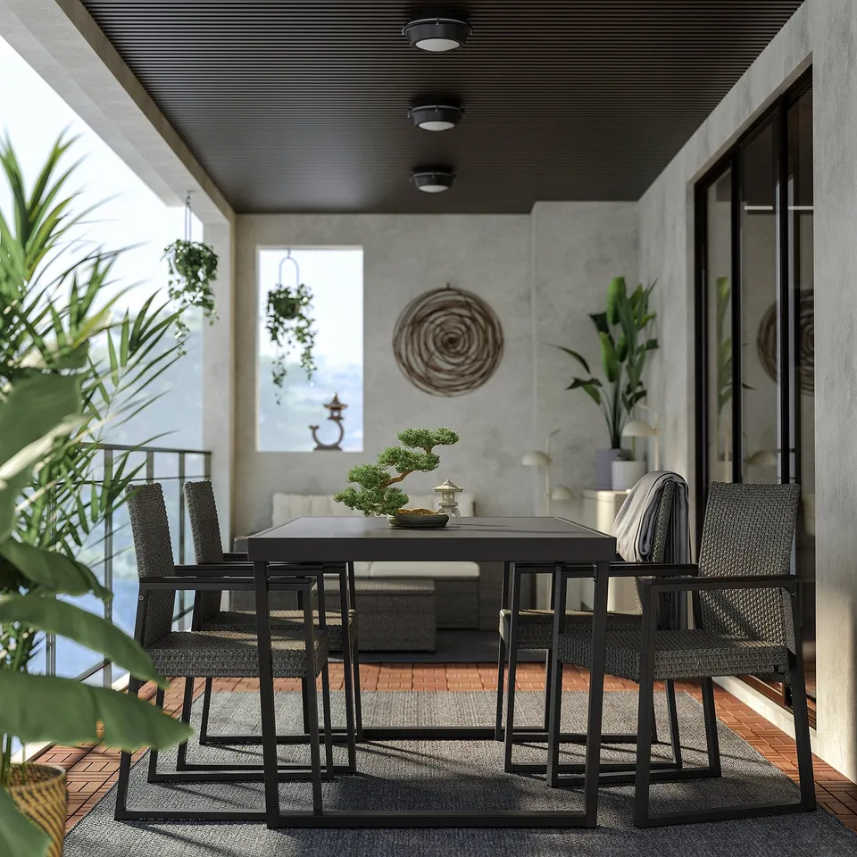 Modern balcony with black metal table and wicker chairs, concrete walls, and plants.
