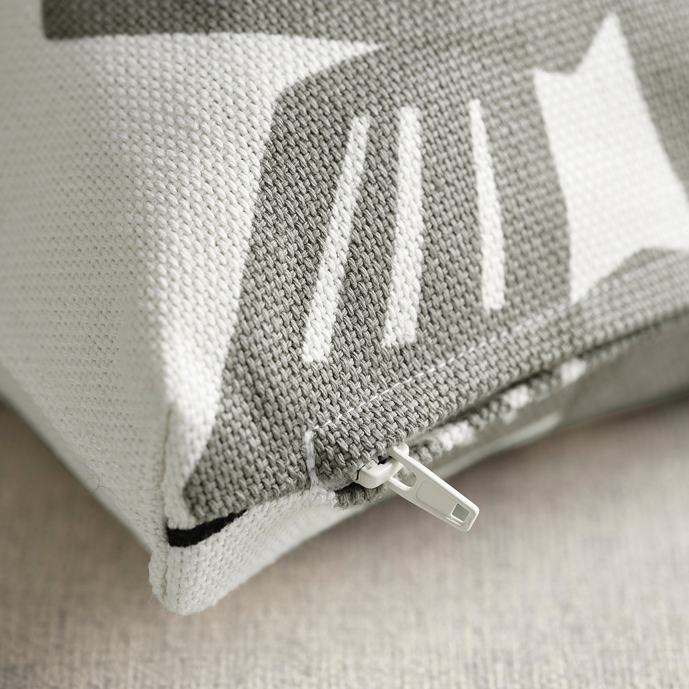Close-up of zip on stylish, high-quality cushion cover with dancing leaf pattern.