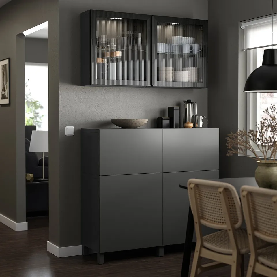 Modern kitchen featuring LAPPVIKEN grey cabinet with sleek design, incorporating glass-fronted cabinets above and a stylish wicker chair beside.