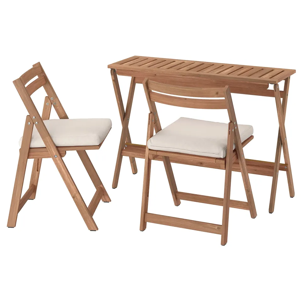Wooden outdoor table and two chairs, beige cushions, foldable design.