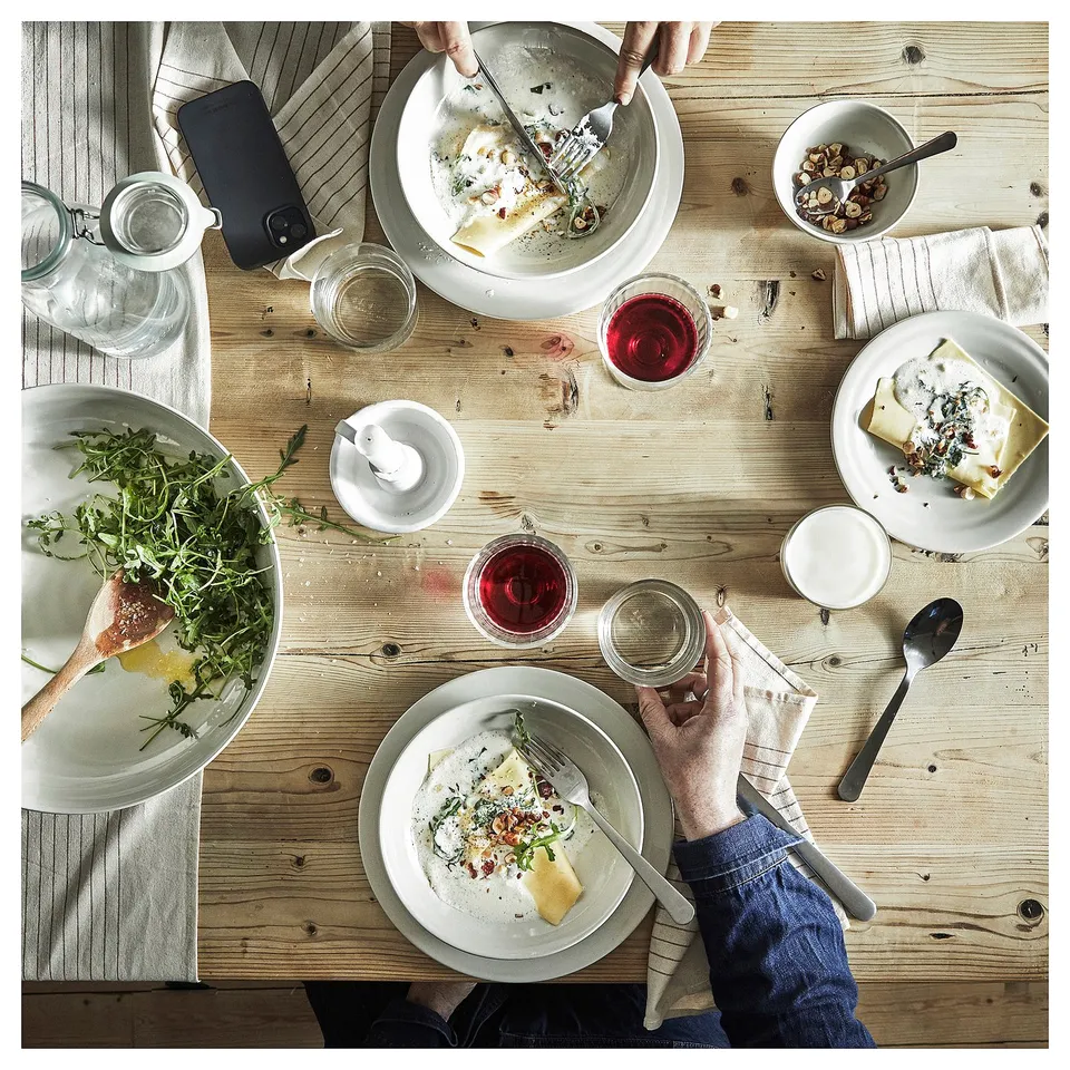 Top view of dining table with rustic earth-toned plates, glasses, and utensils, featuring SANDSKÄDDAs simple, functional design.