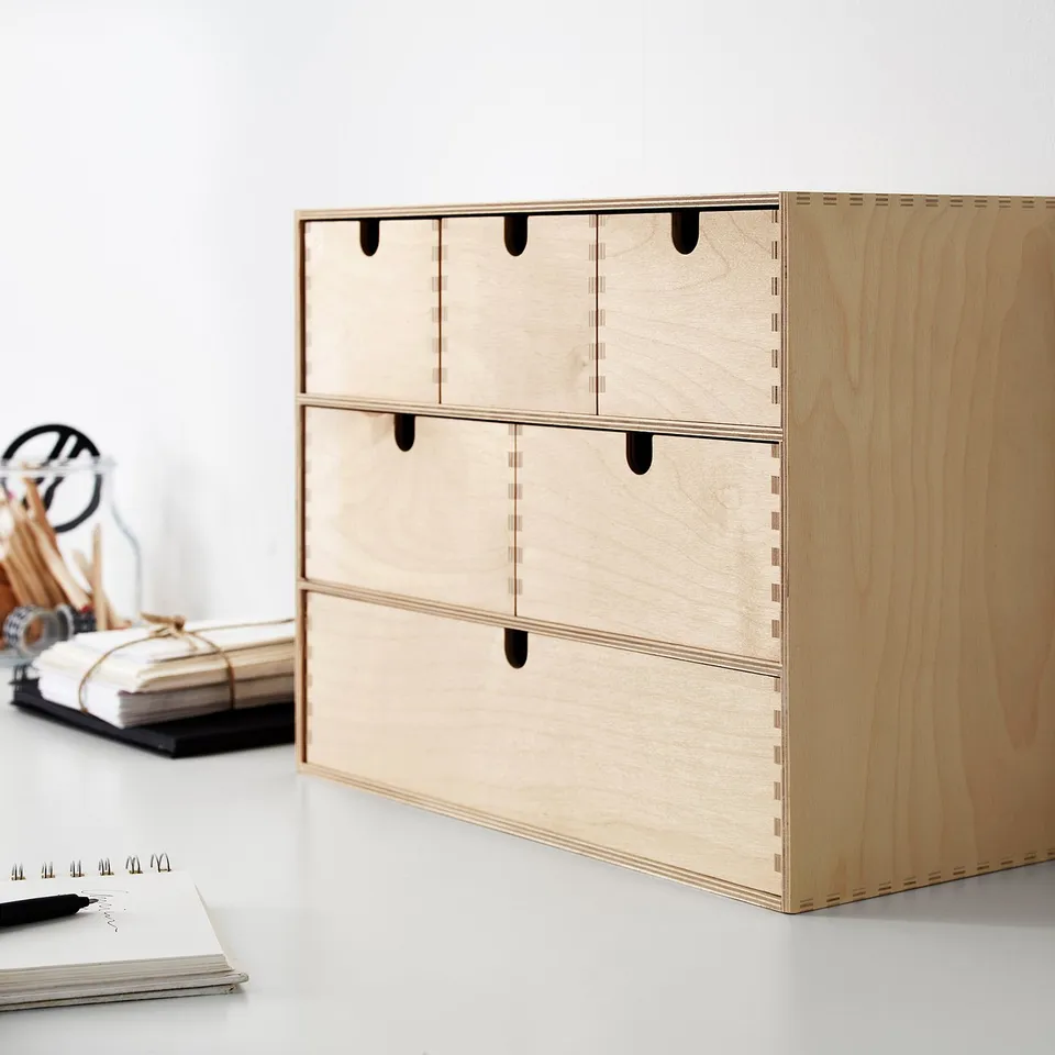 Wooden MOPPE mini chest with six drawers against white wall.