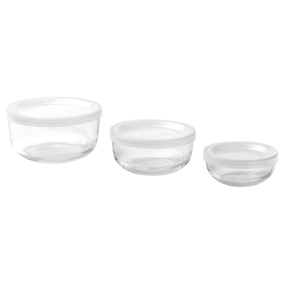 Three clear glass meal prep containers of varying sizes, with transparent lids, neatly stacked for storage.