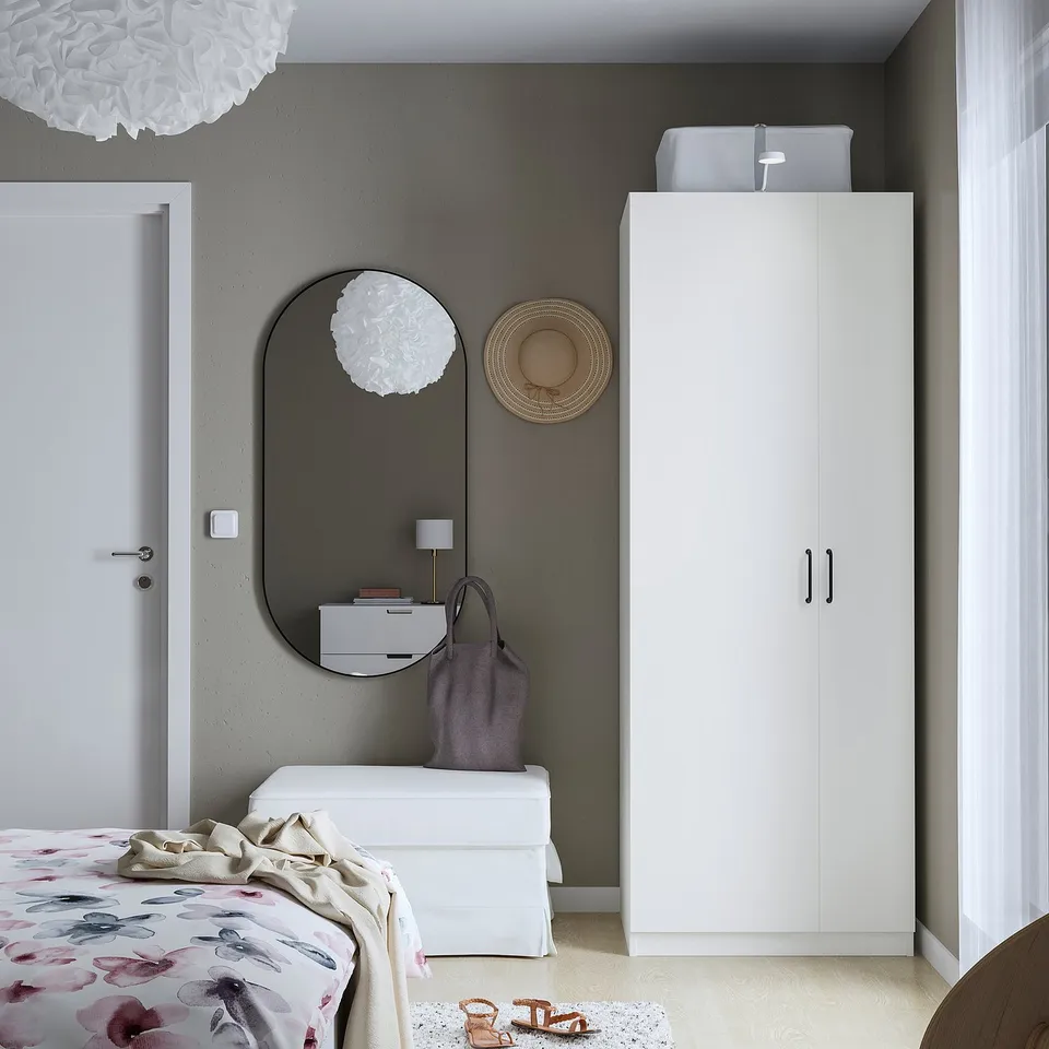 Modern bedroom with PAX wardrobe, mirror, dresser, and floral bed, black handles.