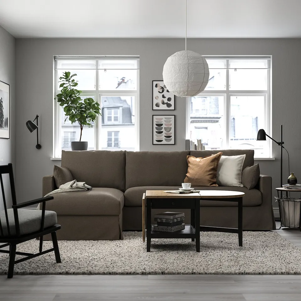 Modern living room: HYLTARP sofa, large windows, light coffee table, black chairs, patterned rug, white orb light.