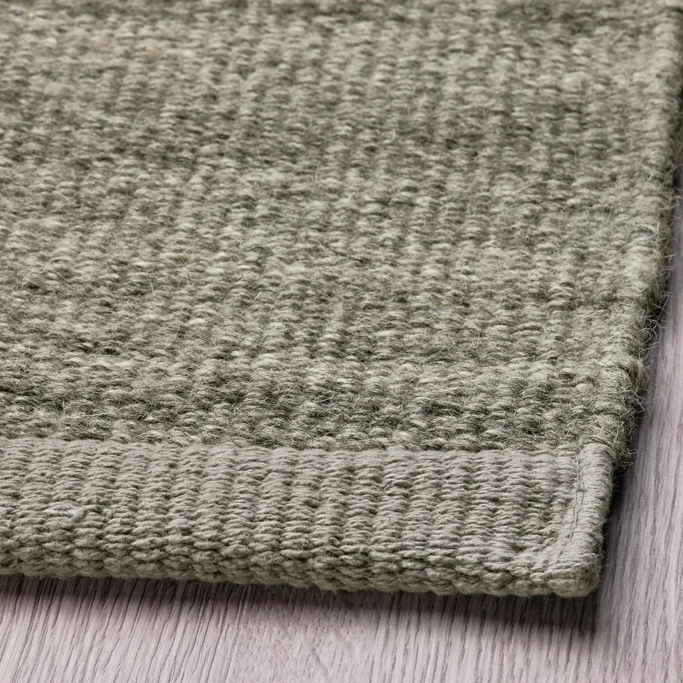 Grey rug corner on wood floor.