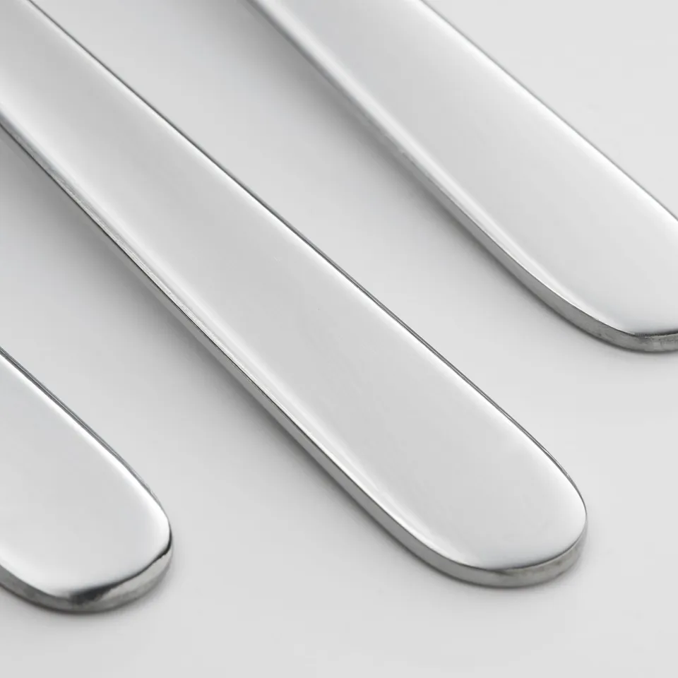 Four polished, shiny, stainless-steel forks arranged neatly, reflecting light, showing high quality and clean design.