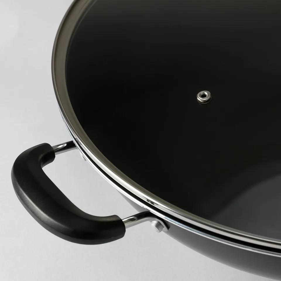 High-quality wok with black phenolic handle and glass lid, showing robust design and non-stick coating.
