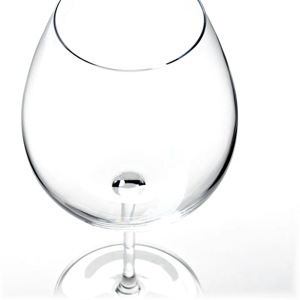 Clear, empty wineglass with long stem, smooth edge, reflecting light, set against white background.