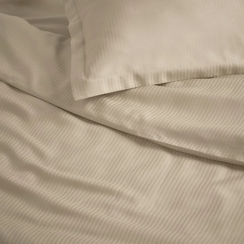 Beige bedding set with subtle pattern, smooth texture, likely made from high-quality lyocell fabric.