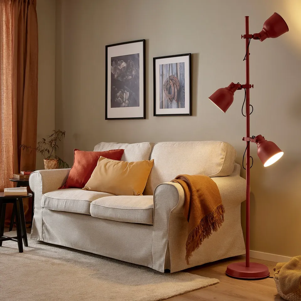 Living room with cream couch, red pillows, lamp, and plant.