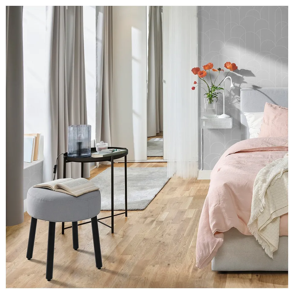 Light wood bedroom, grey walls, floral bedding, side table with cups and candle, sheer curtains.