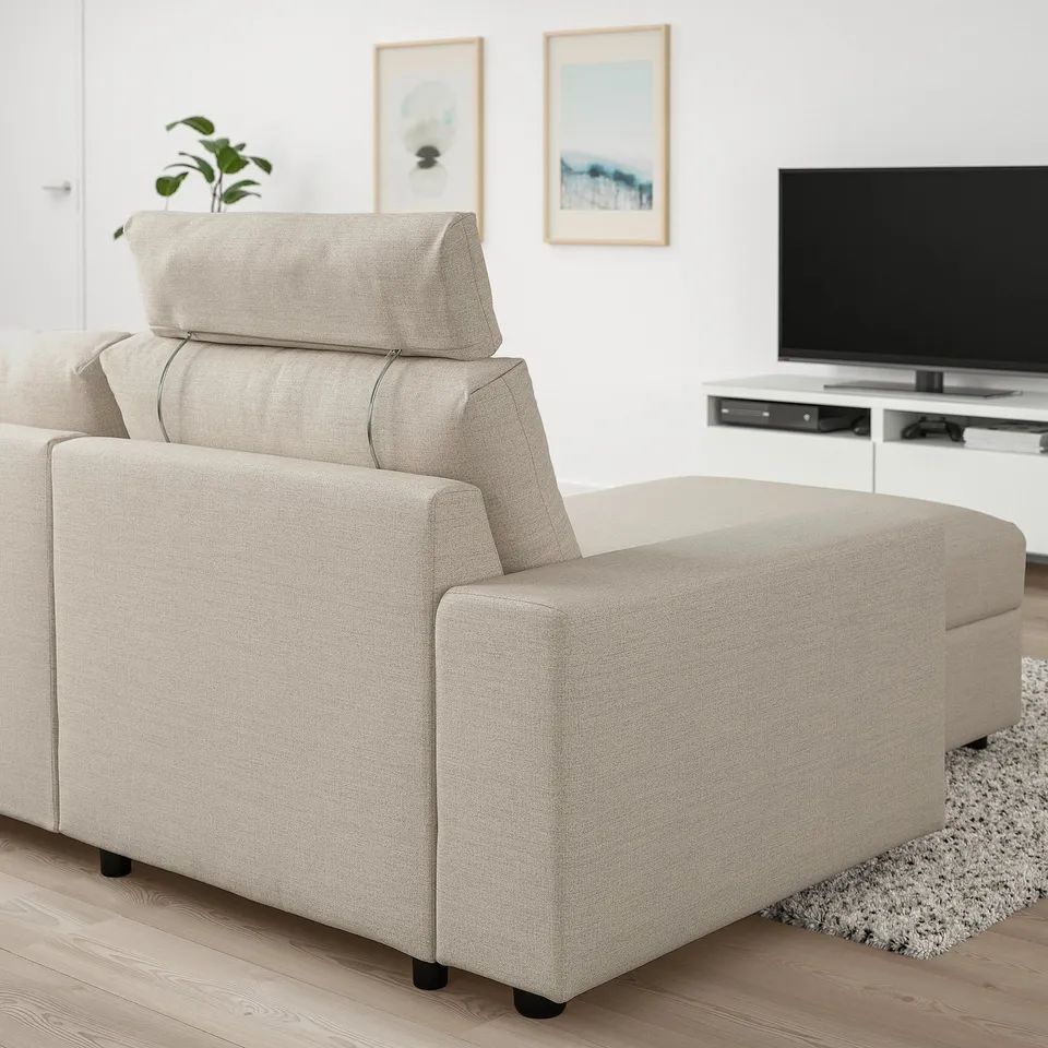 Beige VIMLE sofa section in living room, beside tv on stand, with white walls and framed art.