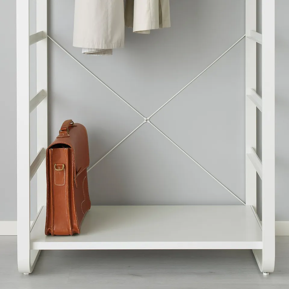 A brown leather bag rests on a white shelf of an adjustable storage unit against a grey wall. The unit has visible metal supports and an open design.