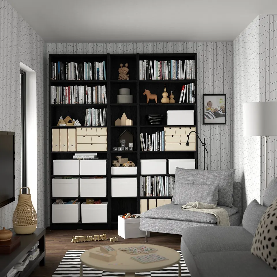 Black BILLY bookcase with books & decor, grey sofa, lamp, striped rug & toys, cosy reading area.
