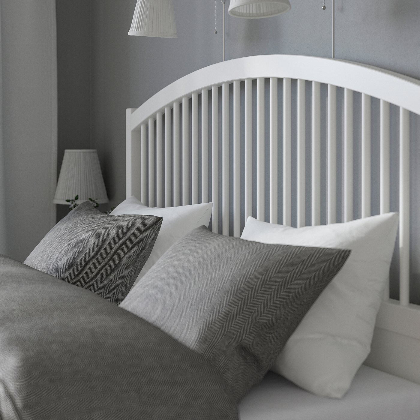 Black and white bedroom scene. White wooden bed with curved headboard, pillows, and lamps.