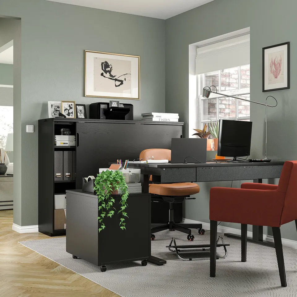 Home office with MITTZON black sit/stand desk, red chair, computer, and green walls.