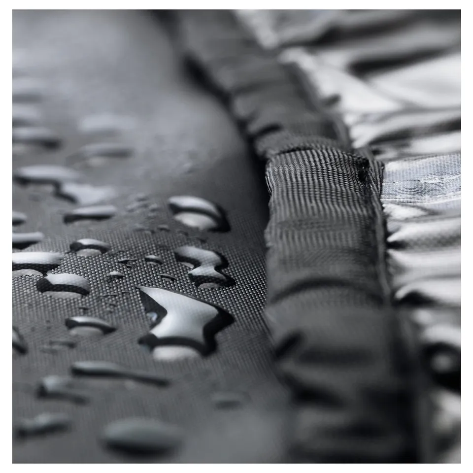 Waterproof furniture cover with water droplets, protecting outdoor dining set or barbecue.