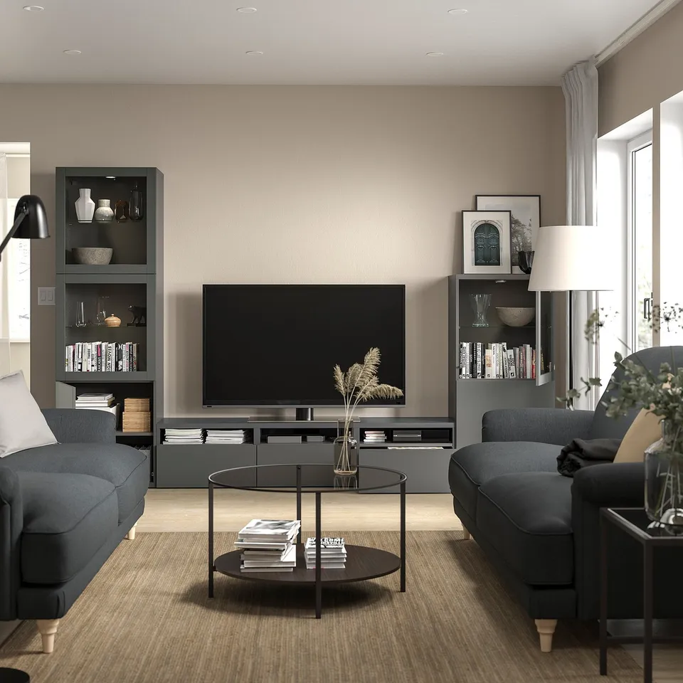 Modern living room with grey sofas, coffee table, flat screen tv, bookshelves, and floor lamp.
