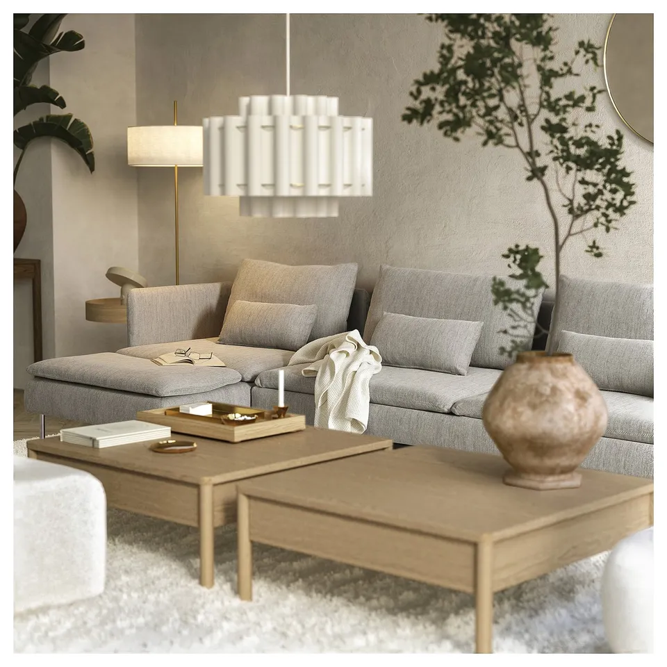 Modern living room with grey SÖDERHAMN sofa-bed, wooden coffee table, white lamp, and houseplant.