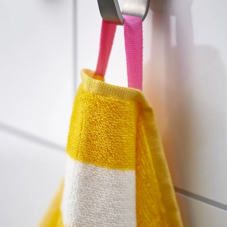 Bright yellow and white striped towel hanging near a window, showcasing its soft, absorbent, and vibrant design.