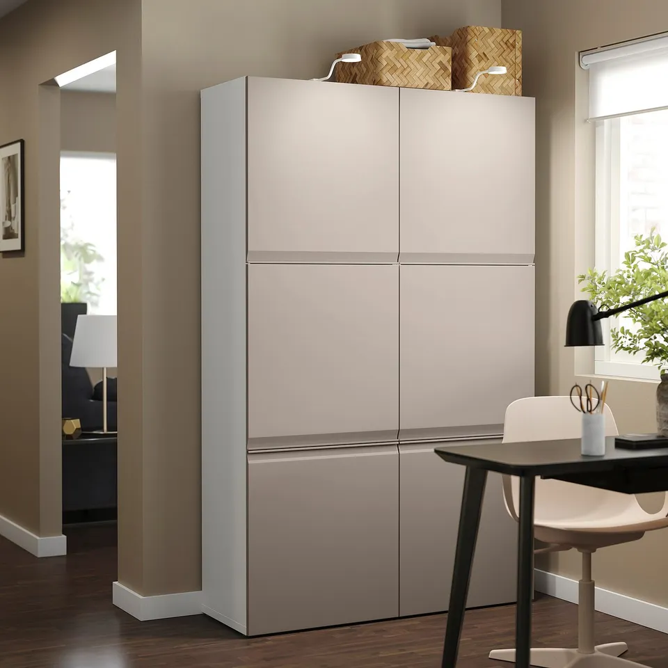 Large grey BESTÅ storage unit with two doors stands by dining table, featuring a sleek, modern design for home organisation.