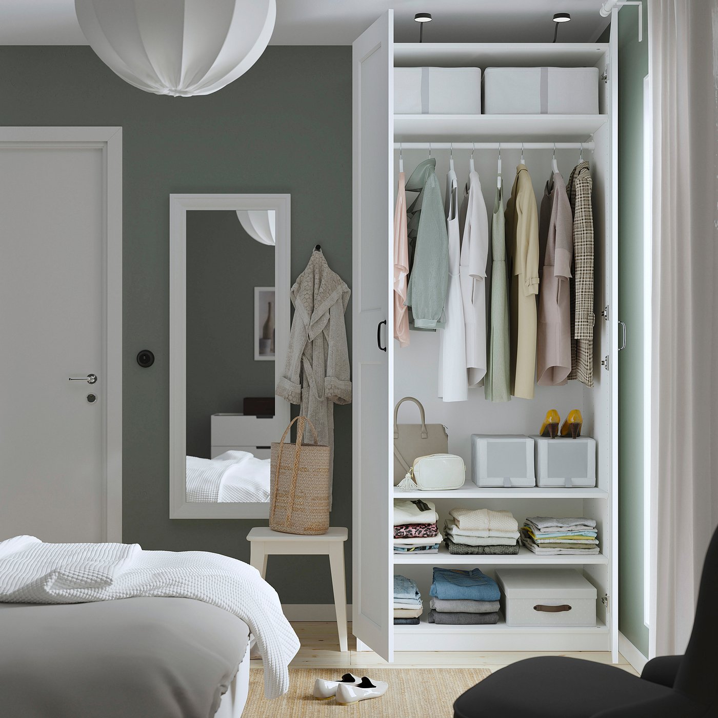 Modern bedroom with white PAX wardrobe, mirror, and bed with linens.