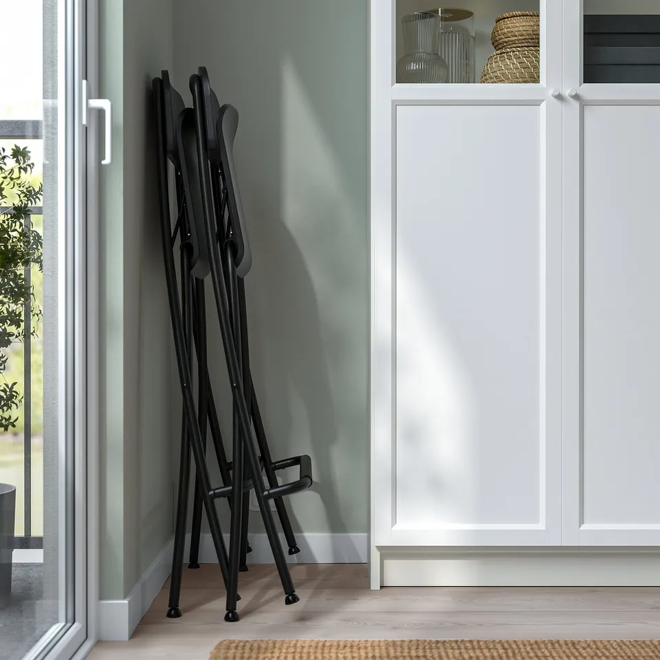 Foldable bar stools stacked neatly against wall, ready for storage.