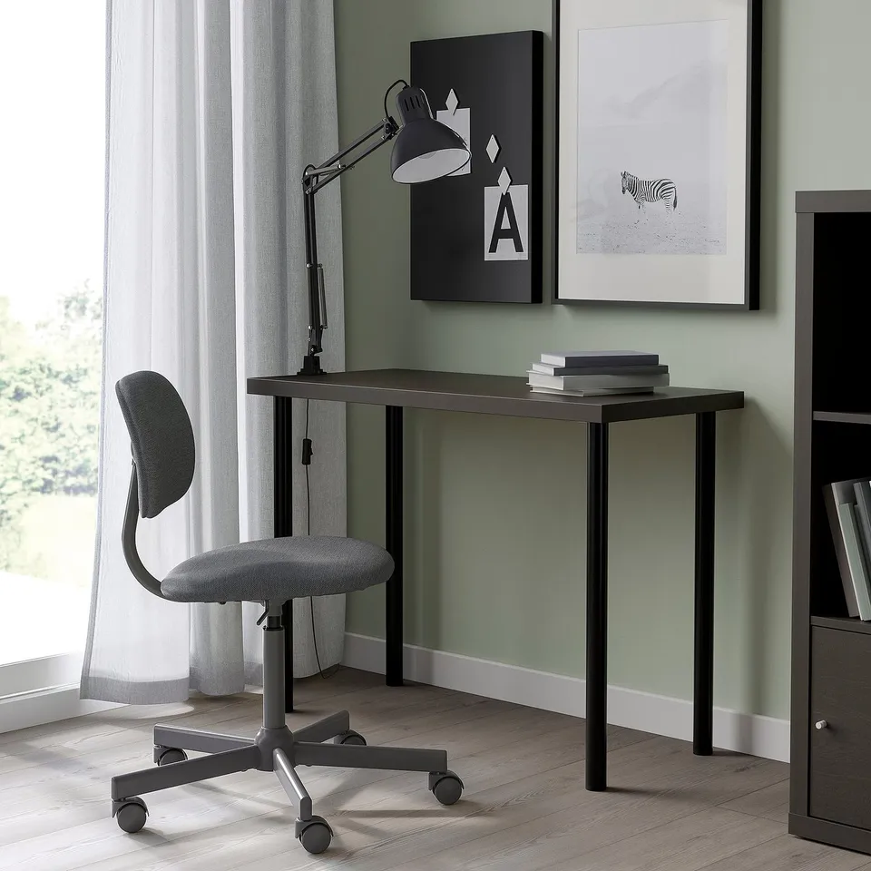 Small, modern grey LINNMON desk with adjustable feet, positioned under architectural art, accompanied by a matching grey swivel chair.