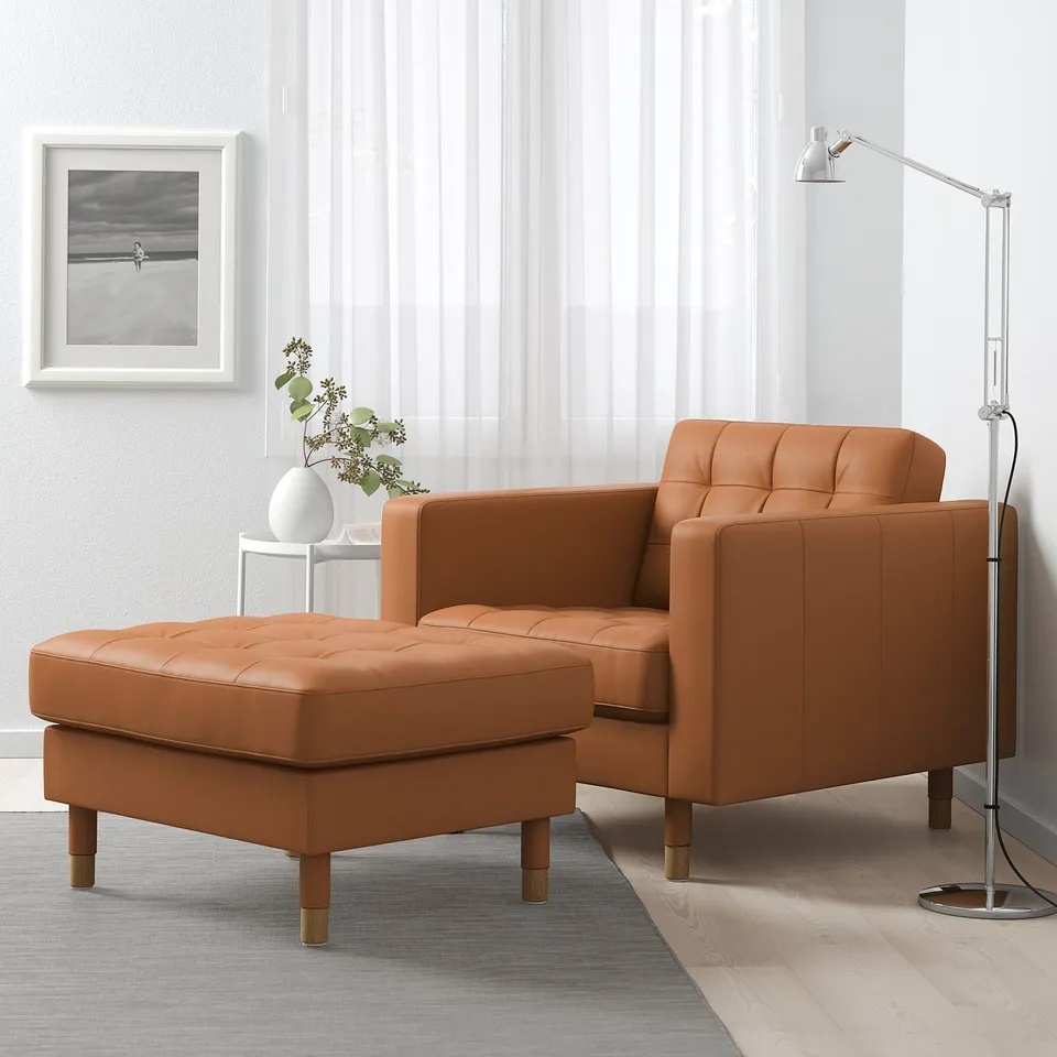 Brown leather armchair, ottoman, tall lamp, white wall, art, flowers.