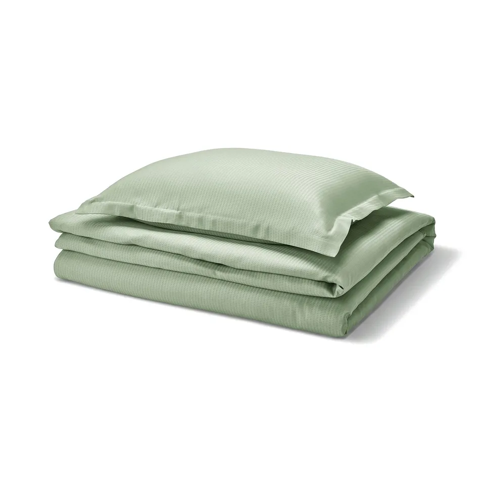 Light green LÄKEVÄNDEROT bed set, folded. Smooth lyocell fabric, button closure, elegant.