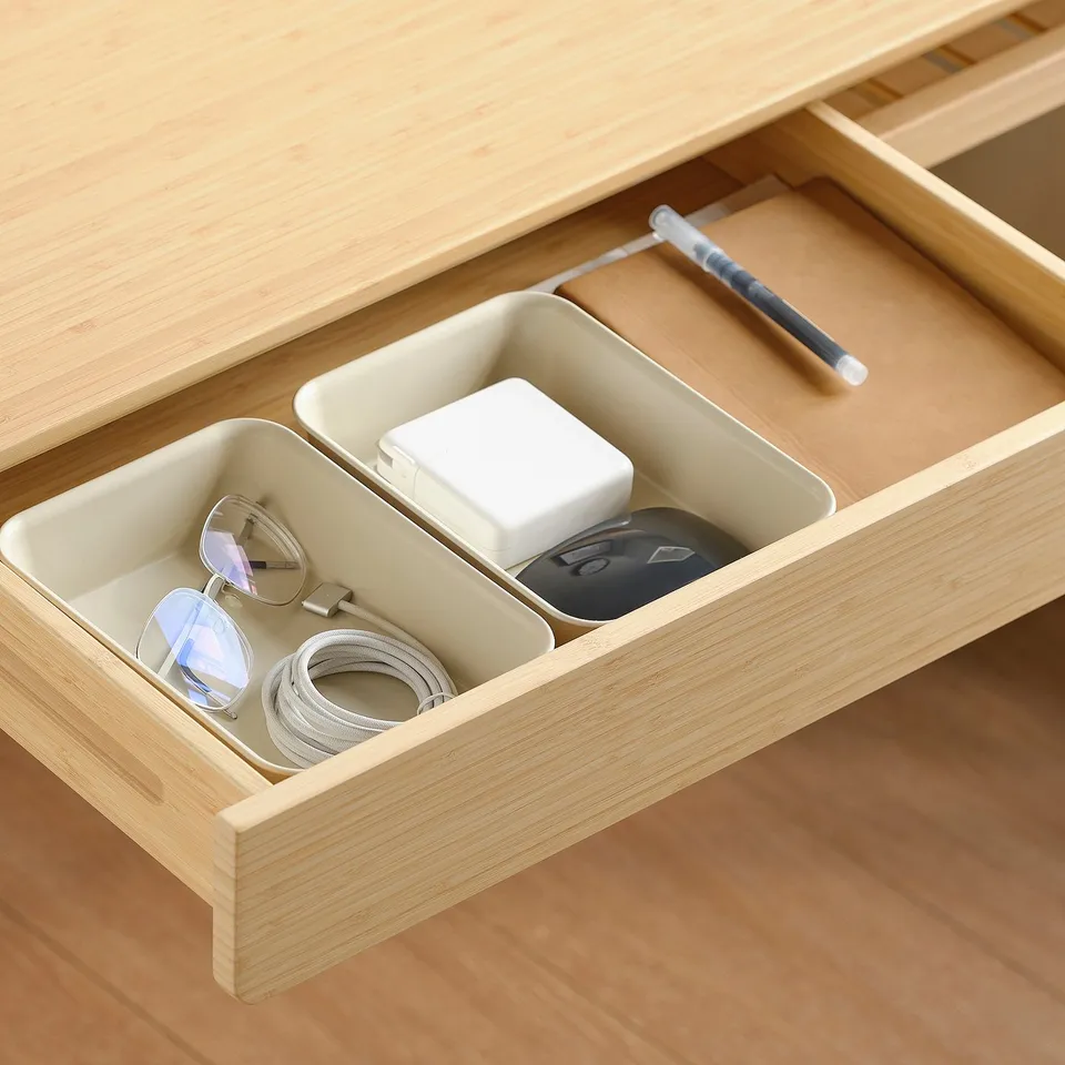 Organised desk drawer with compartments holding glasses, charger, mouse, and pen.