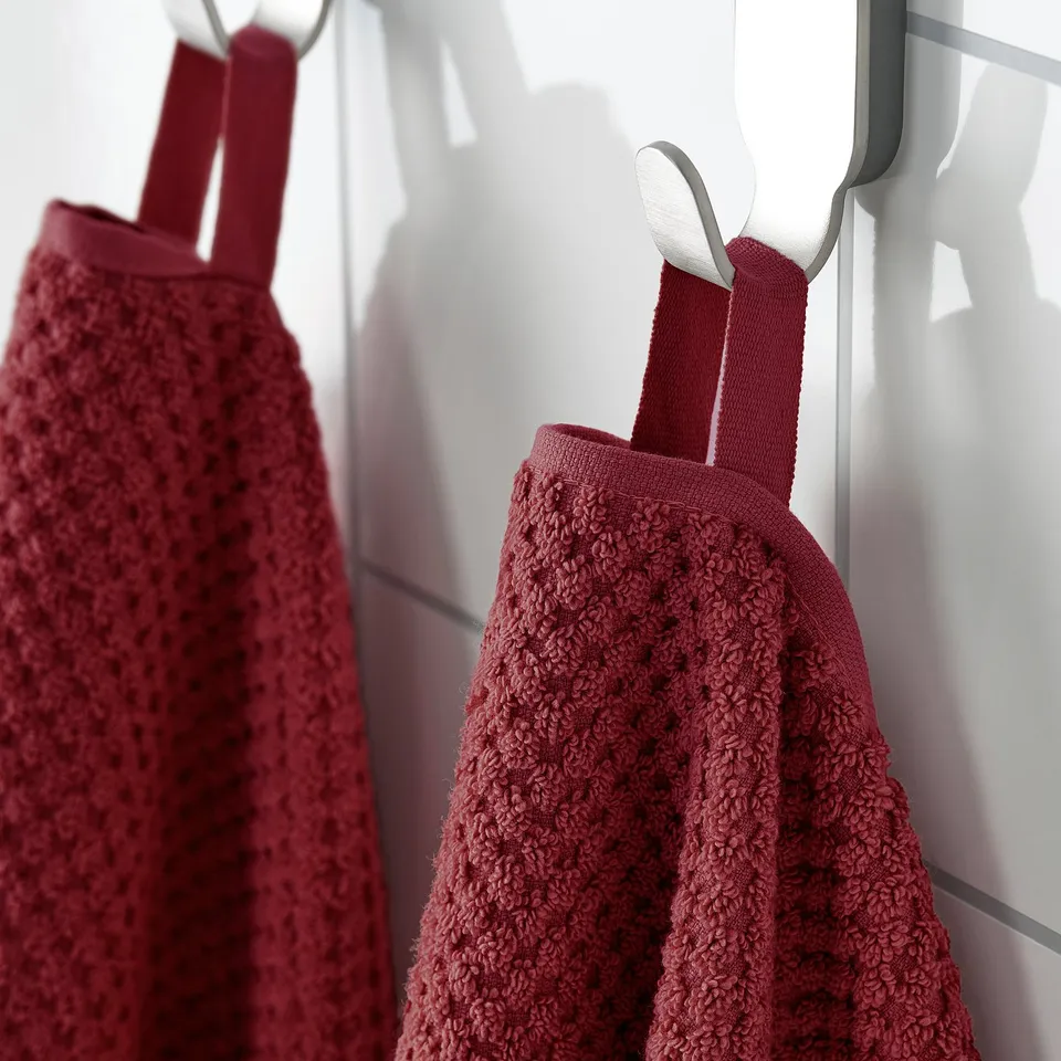 Two burgundy towels hang from hooks. Soft, absorbent cotton; shown in sunny window.