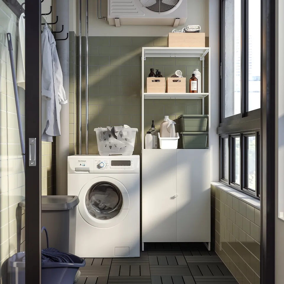 Small white laundry room with washing machine, baskets, and green-tiled walls.