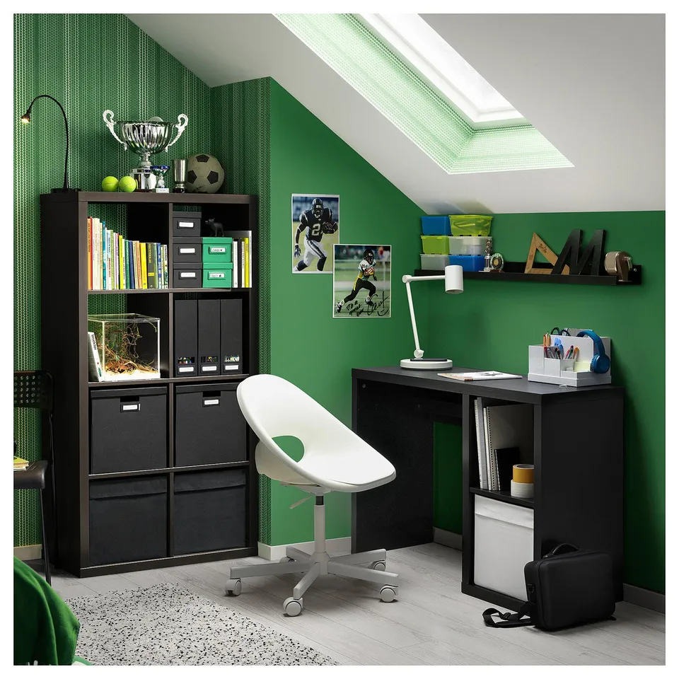 Modern home office with KALLAX desk, chair, and storage in black and white, green walls, sports posters, and natural light from a skylight.