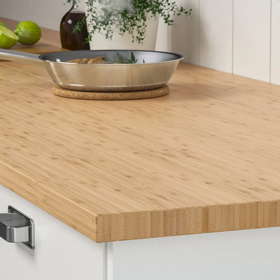 Wooden kitchen countertop with metal pan, plant, and lime fruits.