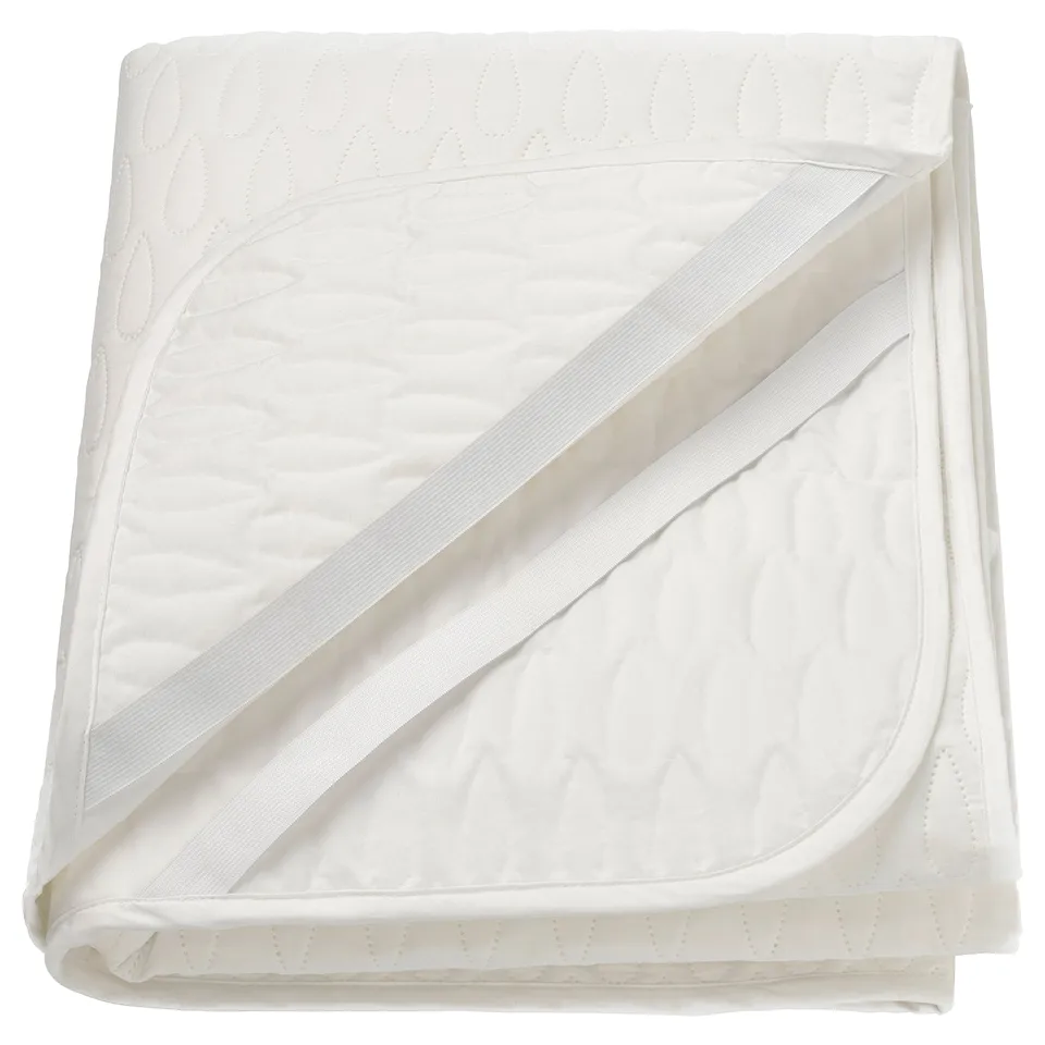 White mattress protector with quilted pattern and diagonal straps.