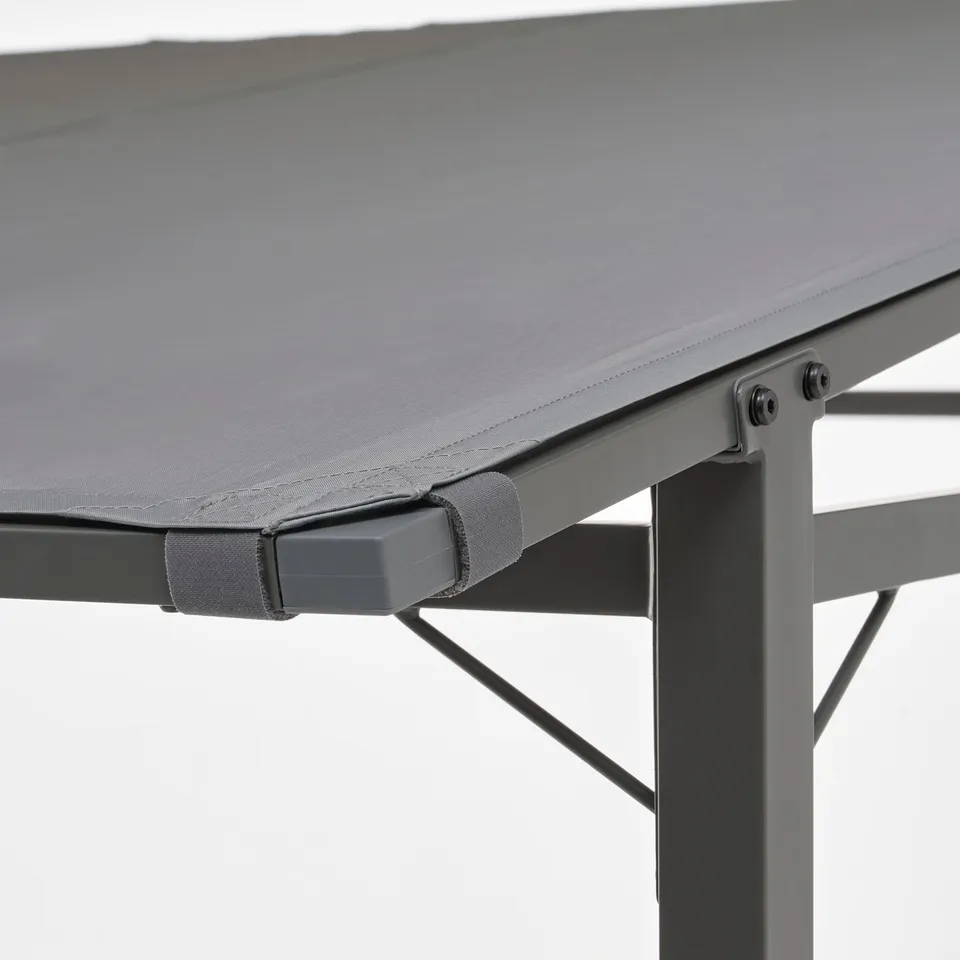 Close-up of foldable table. Grey fabric atop steel frame with adjustable feet, secured by hooks.