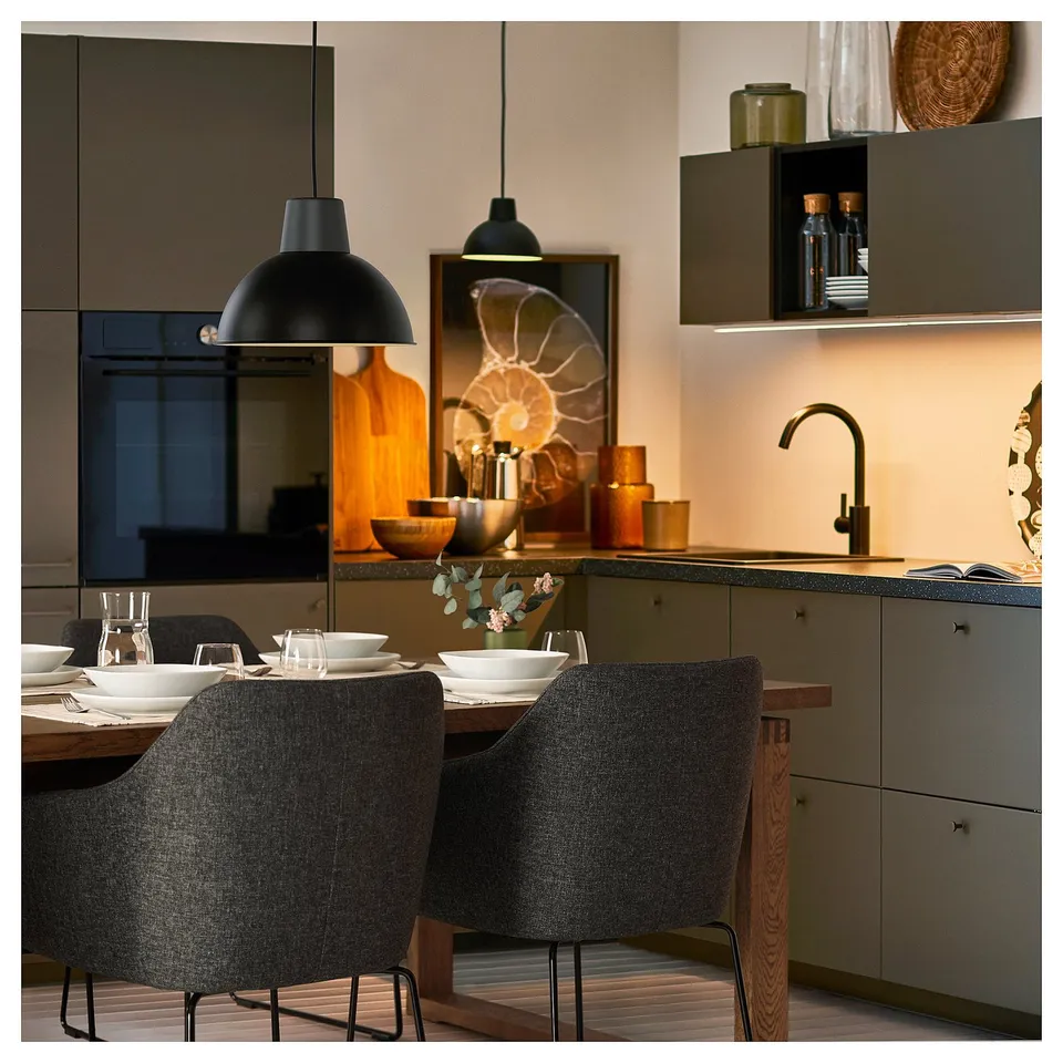 Modern kitchen scene with TOSSBERG grey chairs, wooden table, black pendants, and grey cabinets; warm dining setup.