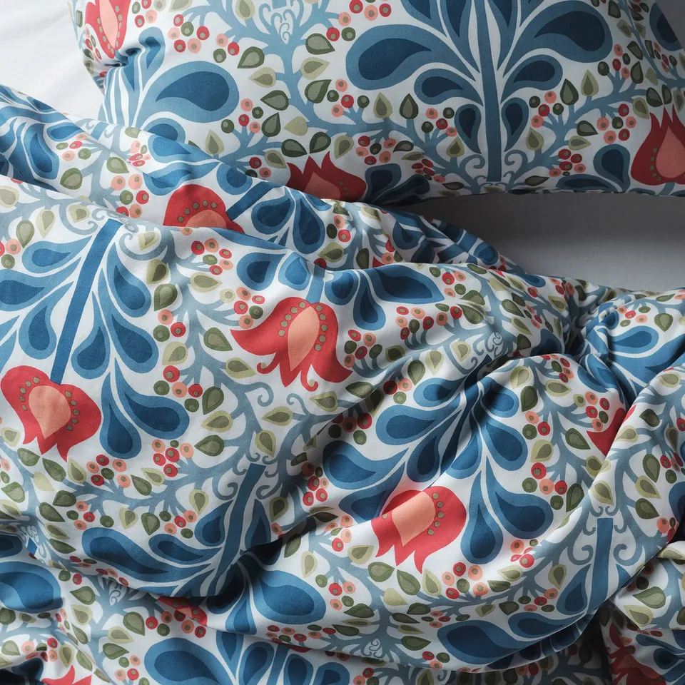 Intricate, colourful floral bedding in blues and red, inviting warmth and relaxation. Soft, durable weave.
