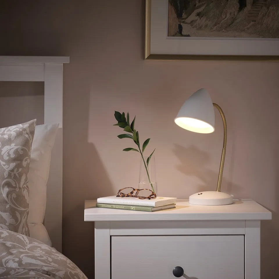 Cosy bedroom with ISNÅLEN retro lamp on bedside table, floral comforter.